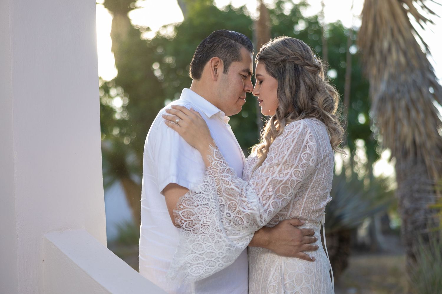 Intimate wedding portrait against white column with palm trees in background. Sesión en Parras Coahuila