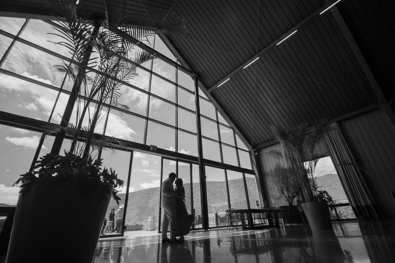 A dramatic black and white architectural photo showing a silhouette against large geometric windows. Boda en Parras Coahuila fotógrafo
