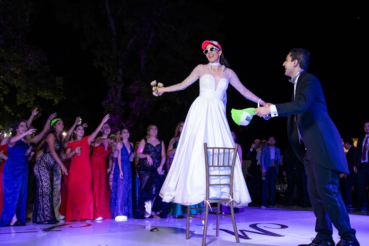 A dramatic dance performance on an illuminated outdoor stage with formal wedding guests watching. Boda en Parras Coahuila, Fotógrafo de boda