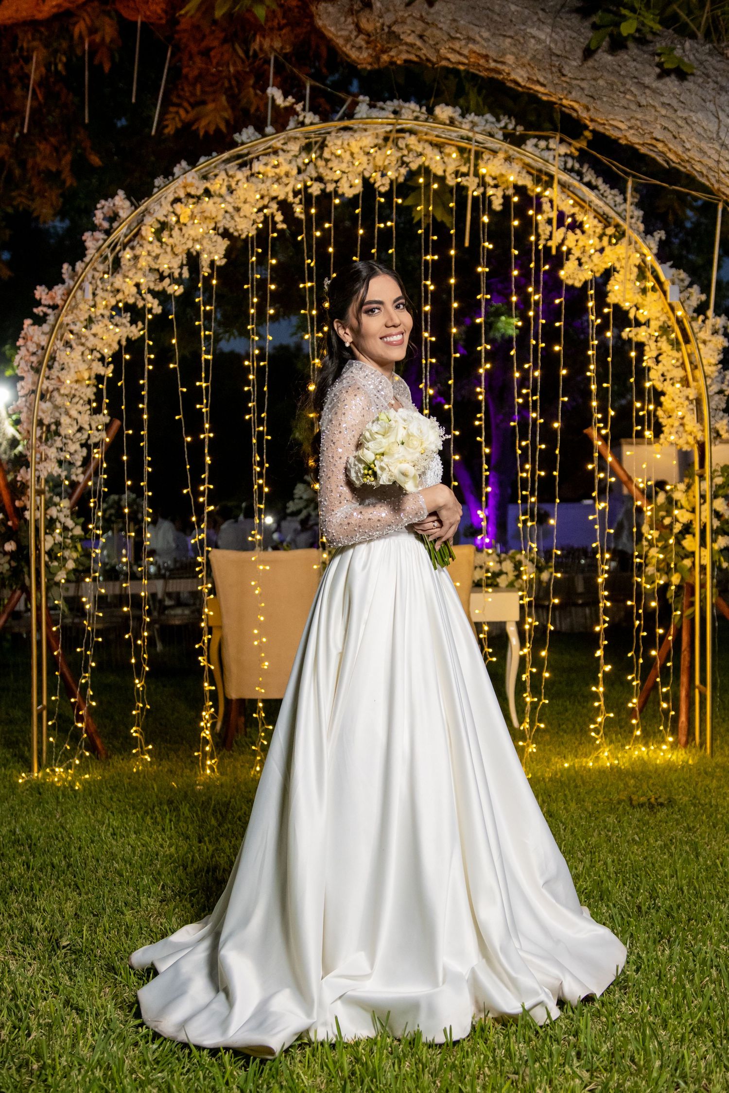 An elegant bridal portrait under an illuminated floral arch with cascading fairy lights. Boda en Parras Coahuila, Fotógrafo de bodas