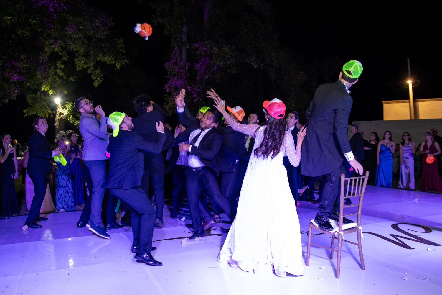 Wedding party dances under purple lighting at an outdoor nighttime reception celebration. Boda en Parras Coahuila, Fotógrafo de bodas