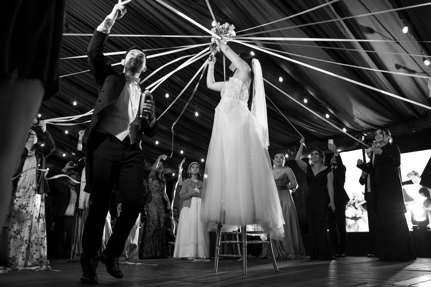 Wedding celebration dance captured in black and white under dramatic ceiling lighting. Boda en Parras Coahuila fotógrafo