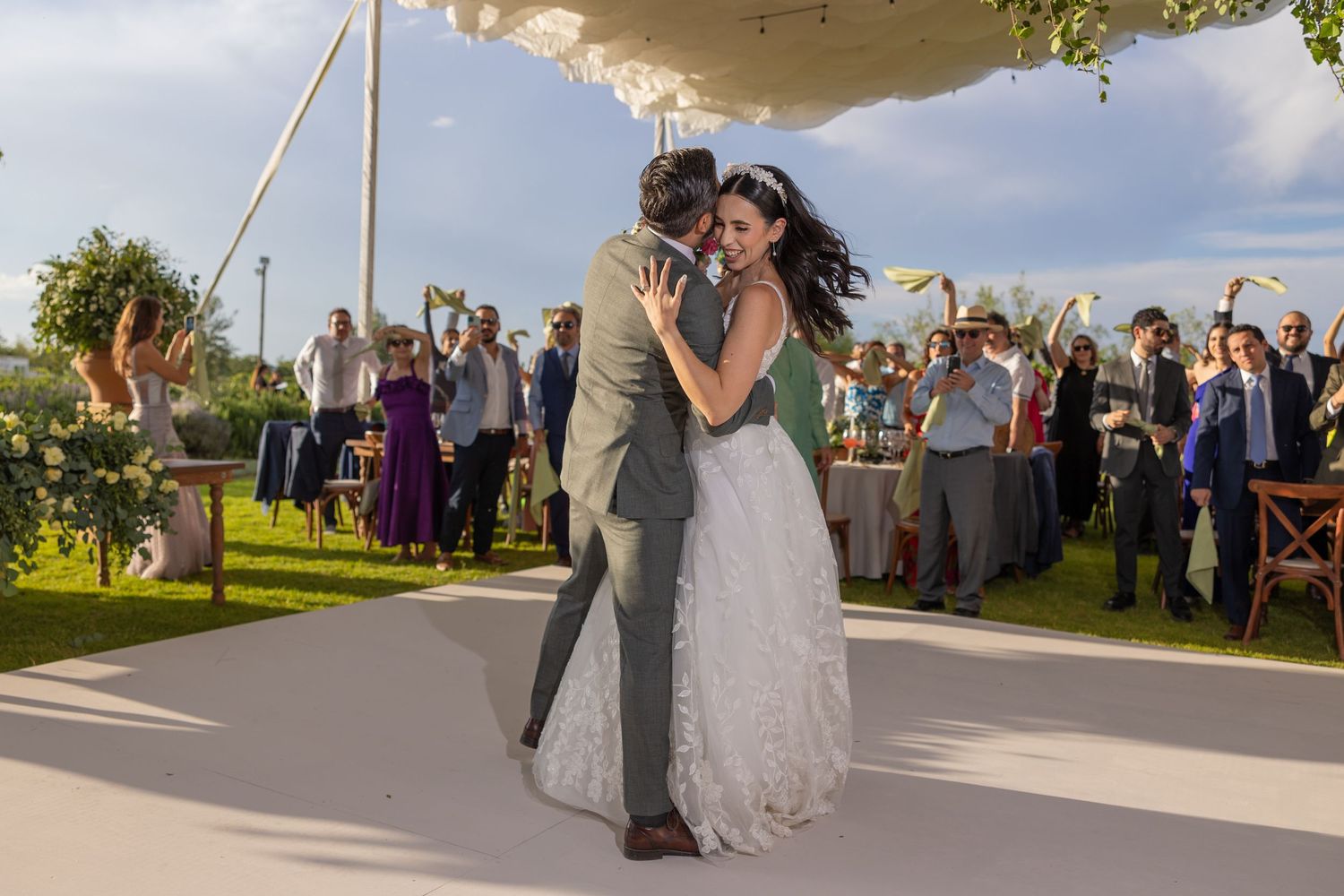 Dancing couple share an intimate moment on outdoor dance floor as guests cheer in background. Boda en Parras Coahuila fotógrafo