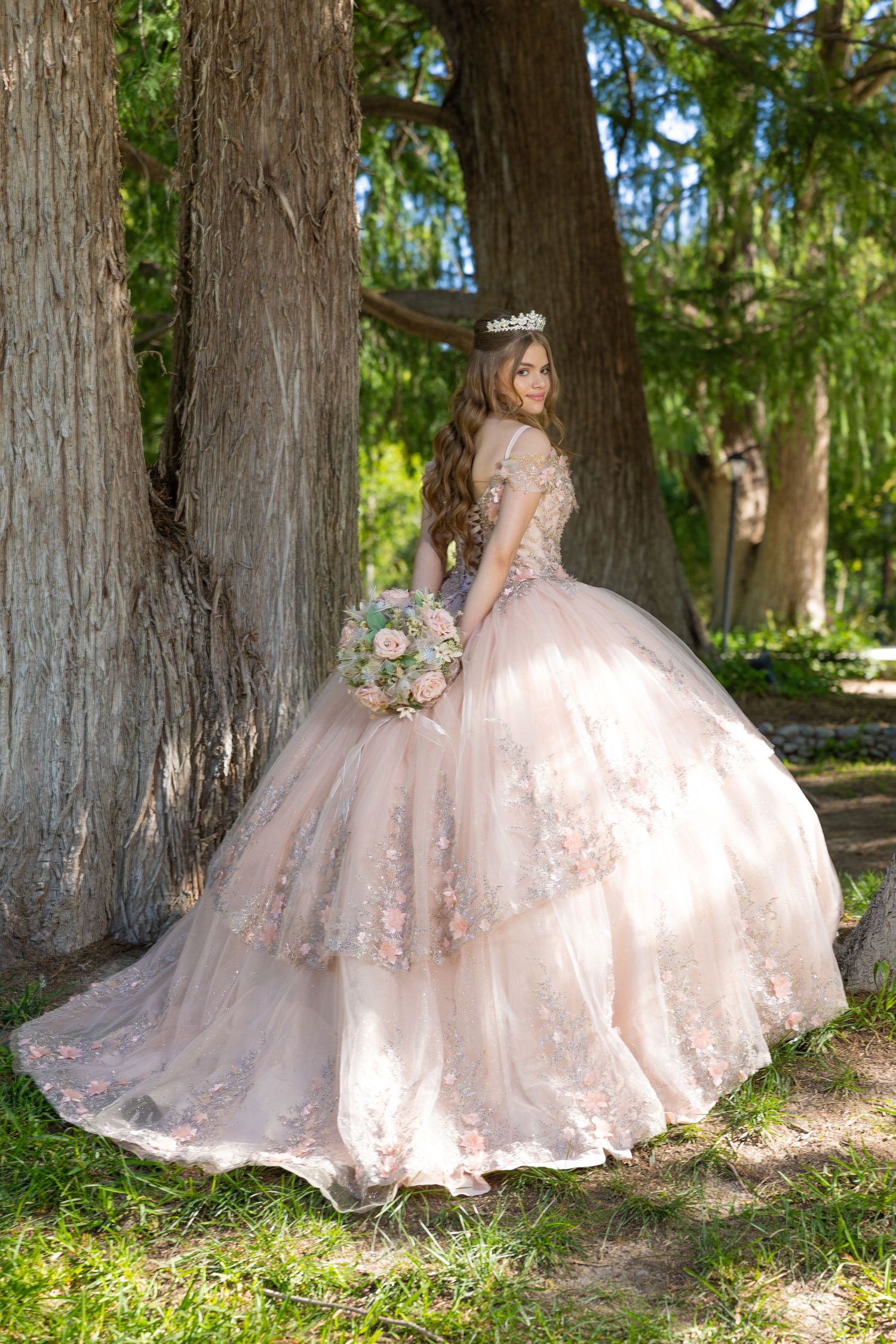 A princess-style ball gown with floral details photographed between majestic trees in natural light. Evento en Parras Coahuila , Fotógrafo