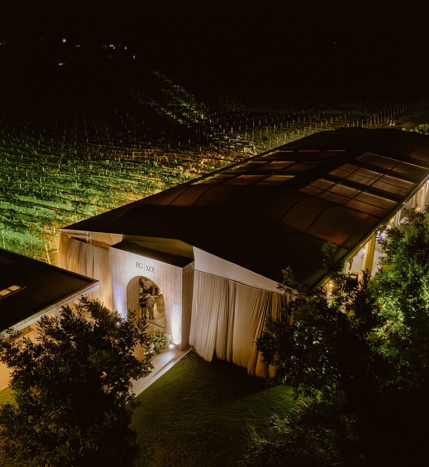 Nighttime view of illuminated modern homes with landscaping and architectural lighting creating a warm ambiance.