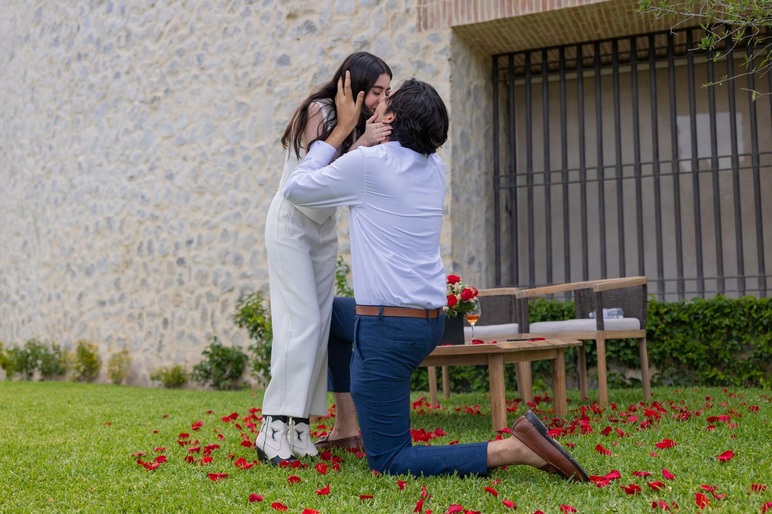 A couple sharing their first embrace after getting engaged on a grassy lawn with rose petals. Propuesta de matrimonio Parras, Fotografo