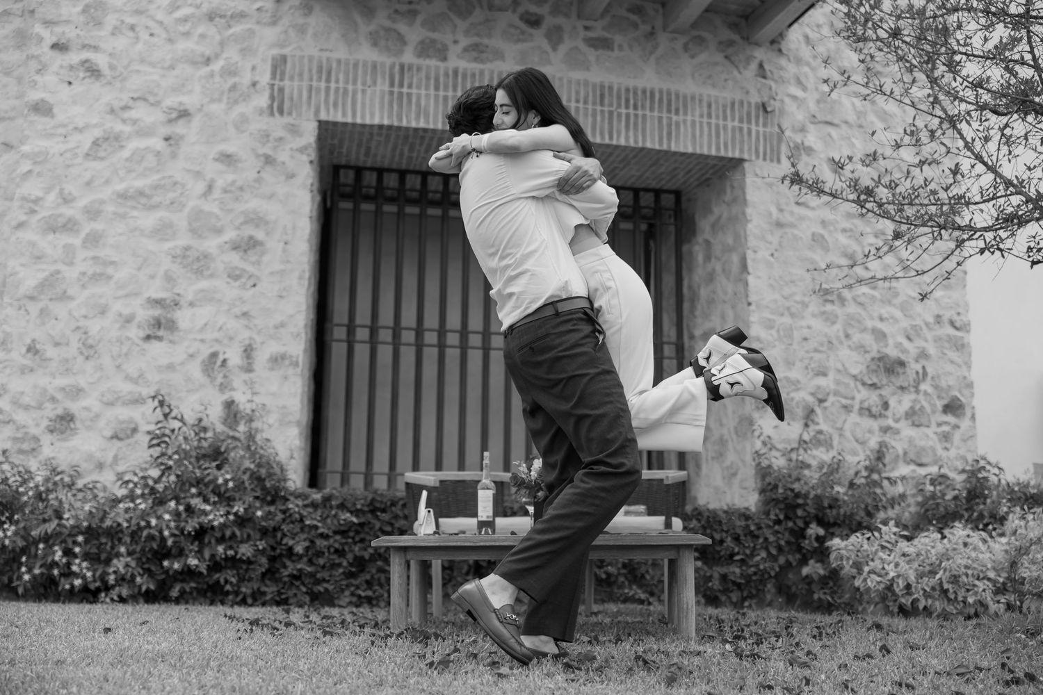 A black and white photo of a couple sharing a joyful moment on a wooden bench. Propuesta de matrimonio Parras, Fotografo