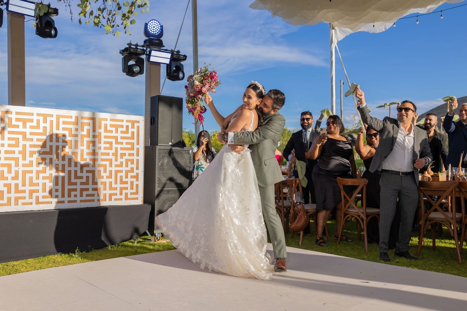 Celebration on an outdoor dance floor with decorative geometric panels and mountain views. Boda en Parras Coahuila fotógrafo