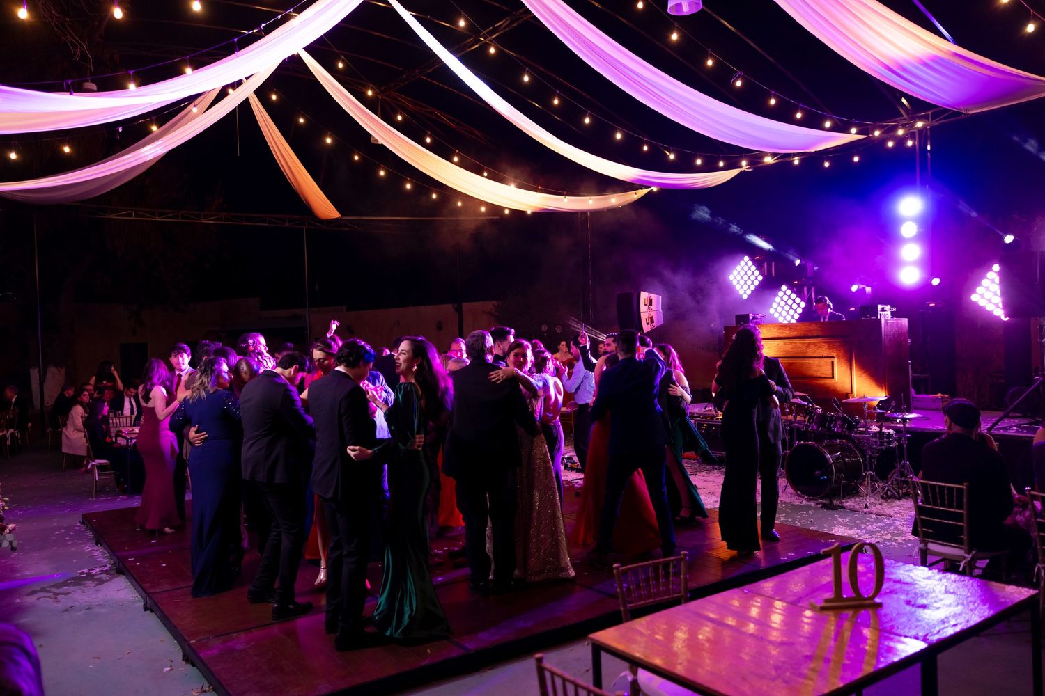 Wedding reception venue with draped fabric ceiling and purple lighting as guests dance. Boda en Parras Coahuila, Fotógrafo de bodas