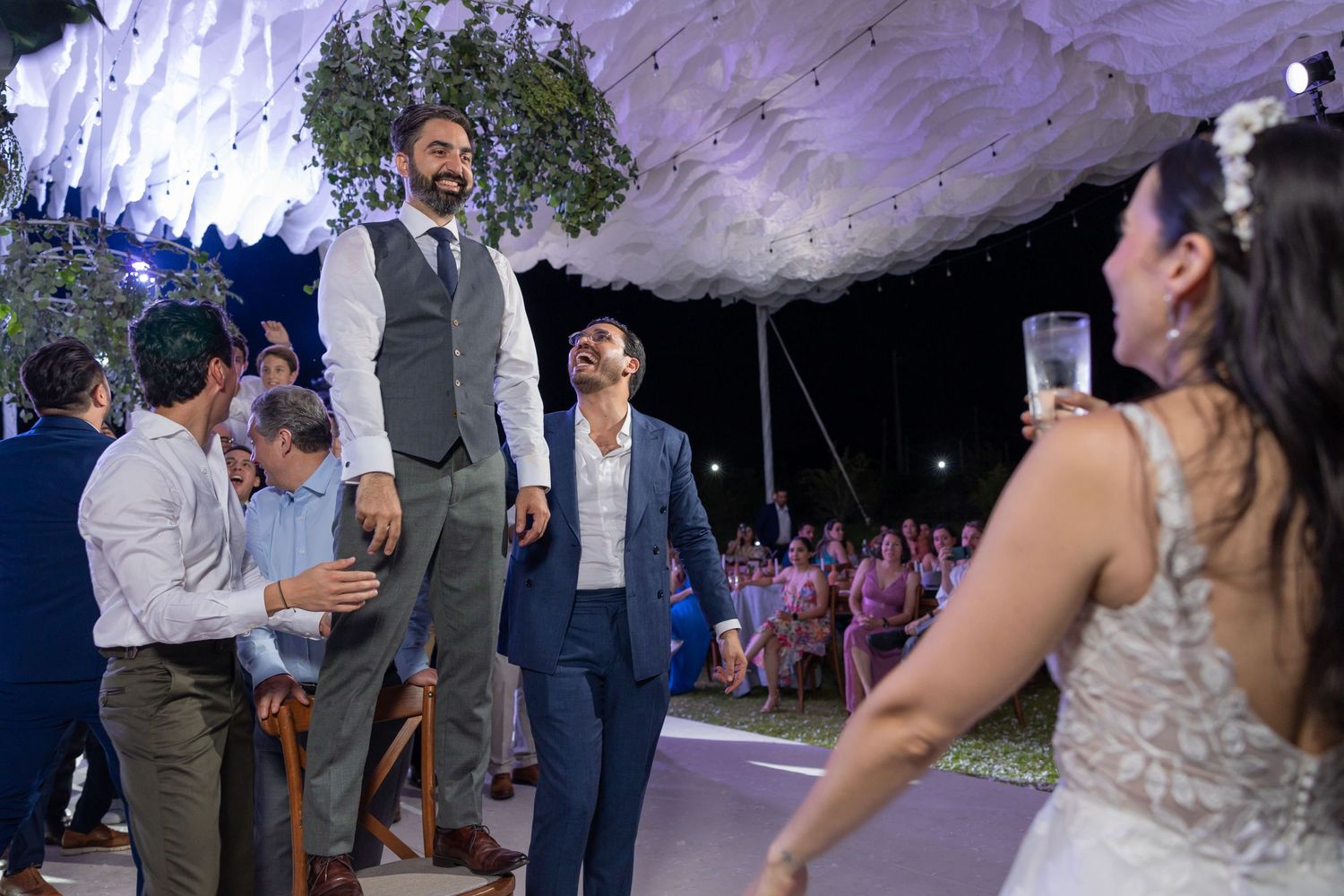 Dynamic wedding reception dance scene with guests celebrating under draped fabric and hanging greenery. Boda en Parras Coahuila fotógrafo