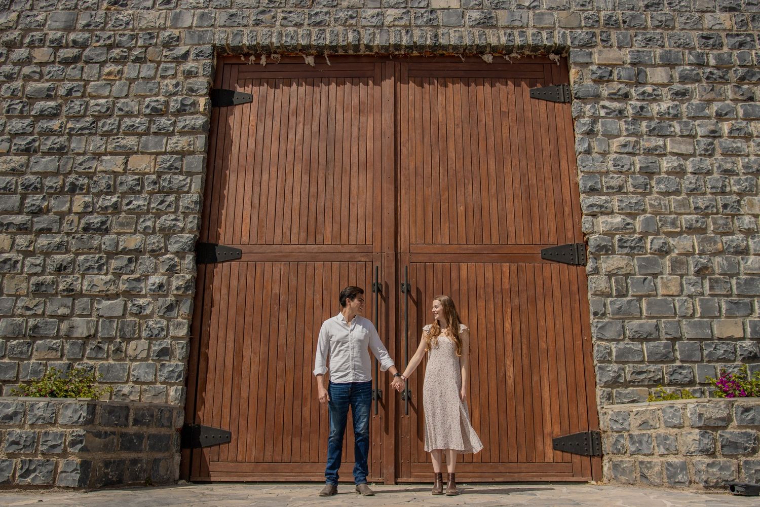 A rustic wedding photo against a large wooden door and stone wall background. Boda en Parras Coahuila fotógrafo