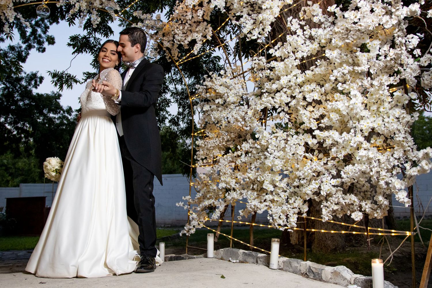 Wedding couple shares romantic moment near illuminated cherry blossom tree at dusk. Boda en Parras Coahuila, Fotógrafo de bodas