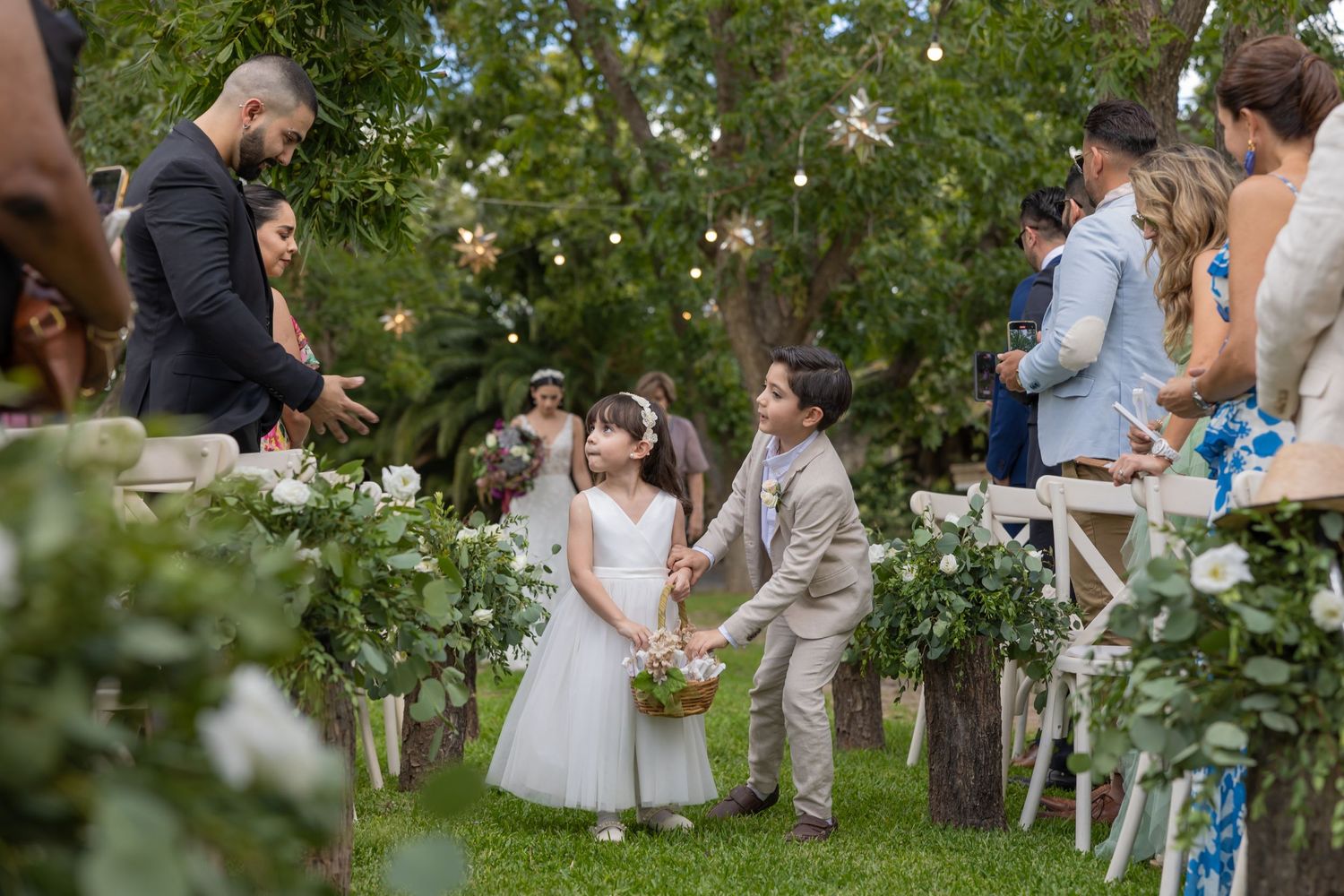 Outdoor wedding ceremony in garden setting with guests seated on white chairs. Boda en Parras Coahuila fotógrafo