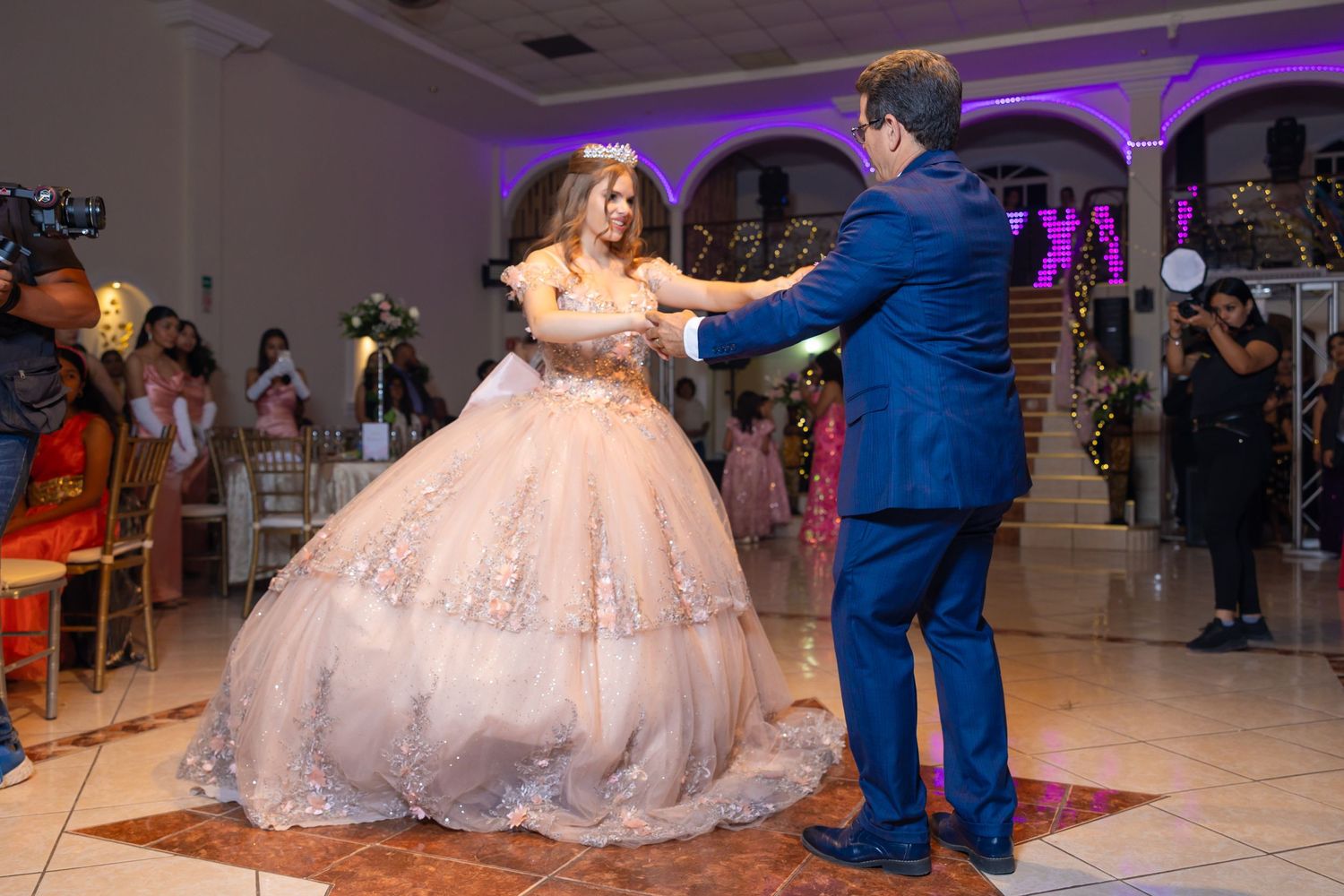 Traditional quinceanera dance moment in ballroom with pink ball gown and blue suit under purple lighting. Evento en Parras Coahuila , Foto