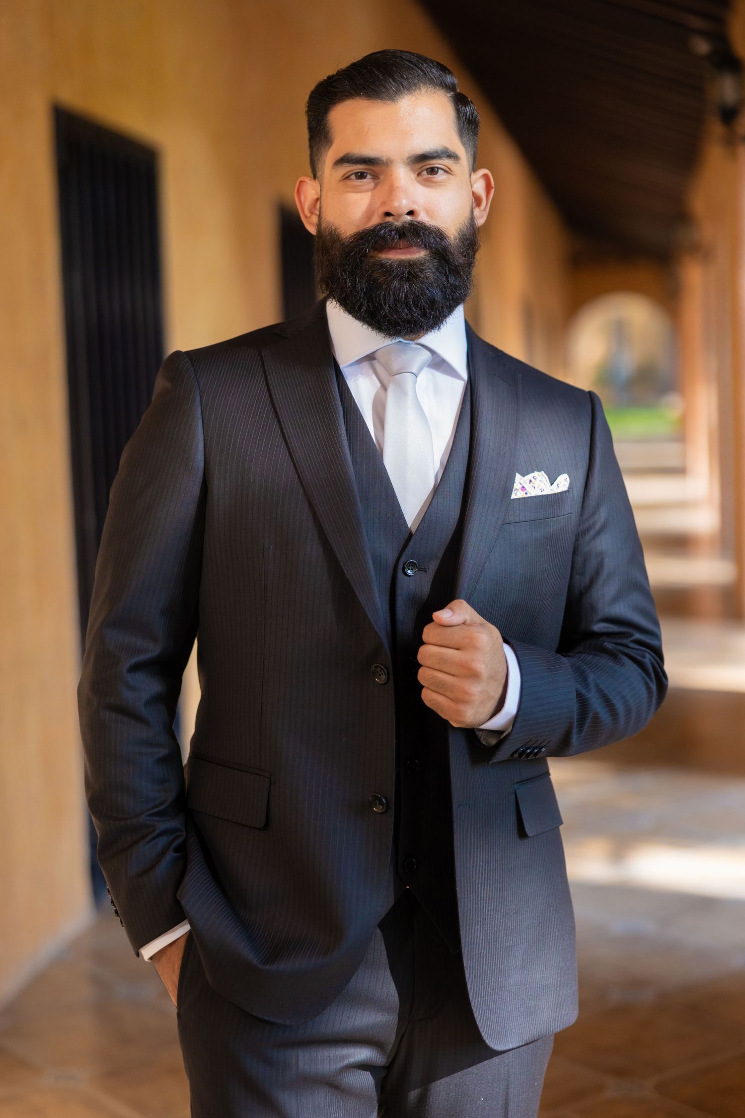A well-dressed groom in a dark three-piece suit and tie poses confidently in an elegant archway. Boda en Parras Coahuila, Fotógrafo de bodas