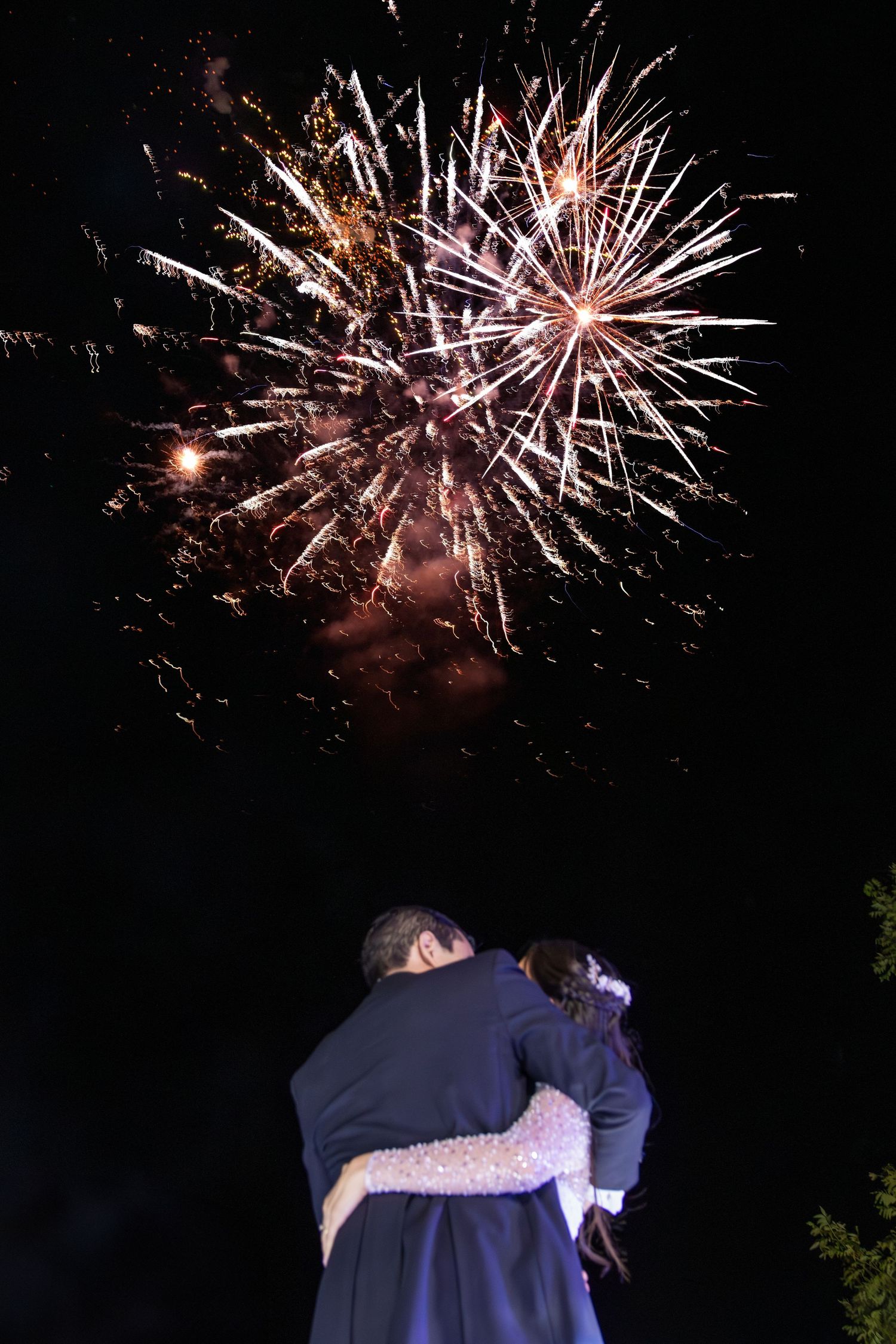 A couple embraces while watching fireworks burst in the night sky during a romantic celebration. Boda en Parras Coahuila, Fotógrafo de bodas