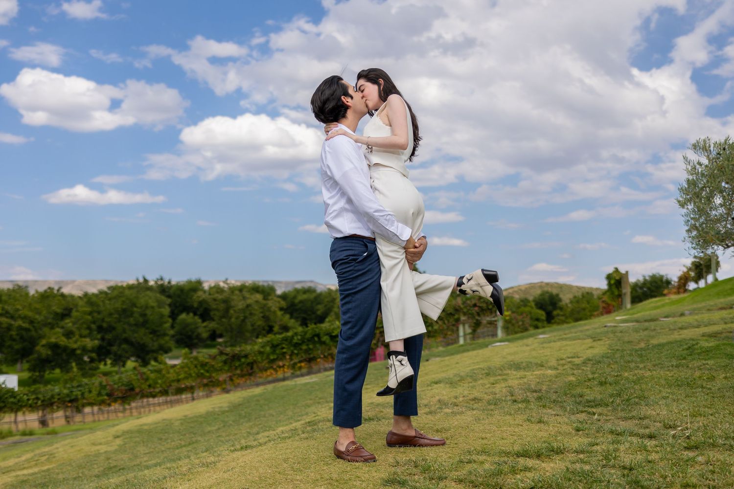 A couple shares an intimate moment while standing on a hillside with scenic views. Propuesta de matrimonio Parras, Fotografo