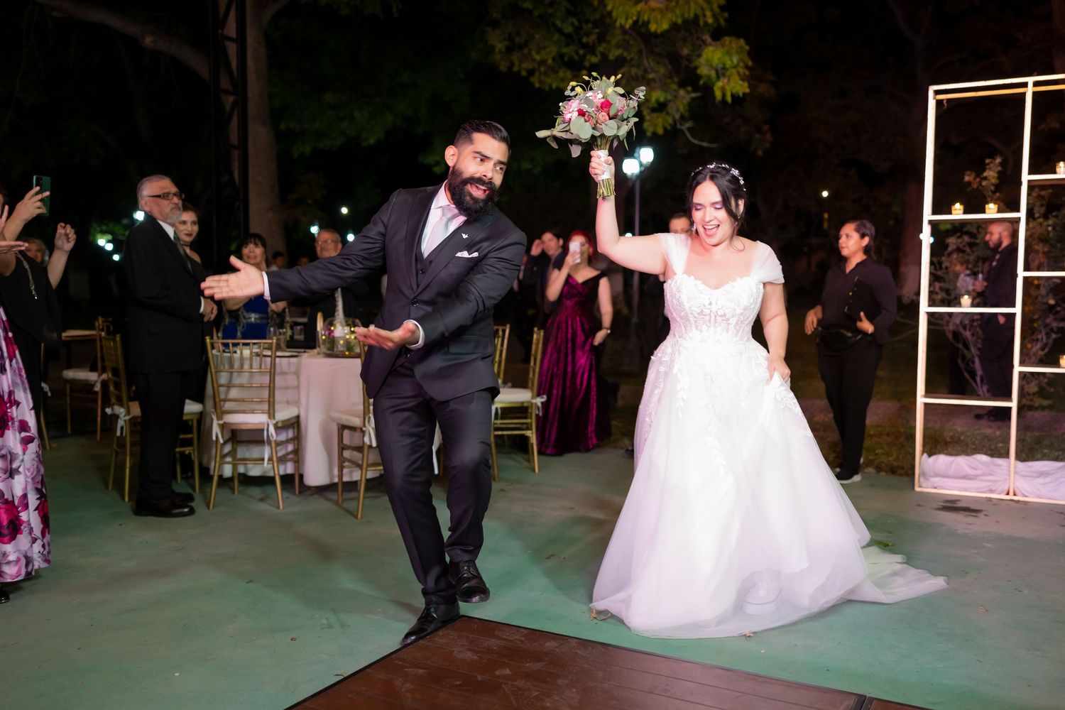 Wedding couple dances with enthusiasm on a wooden dance floor during their outdoor evening reception. Boda en Parras Coahuila, Fotógrafo