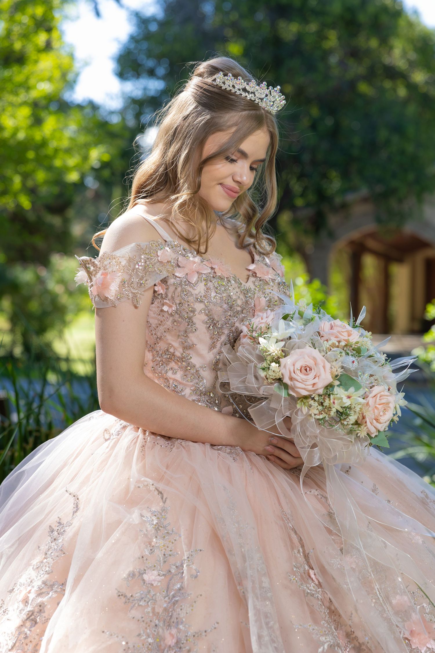 Close-up of pink ballgown with floral details and bouquet in garden setting. Evento en Parras Coahuila , Fotógrafo Rulo