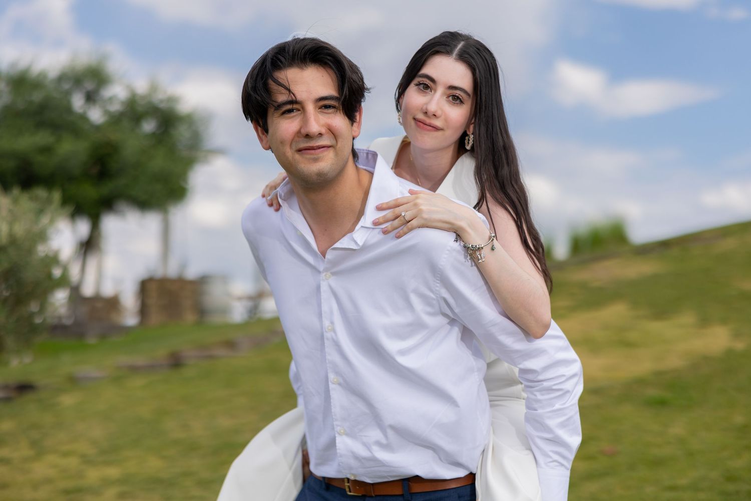 A couple in white outfits shares a playful moment outdoors. Propuesta de matrimonio Parras, Fotografo