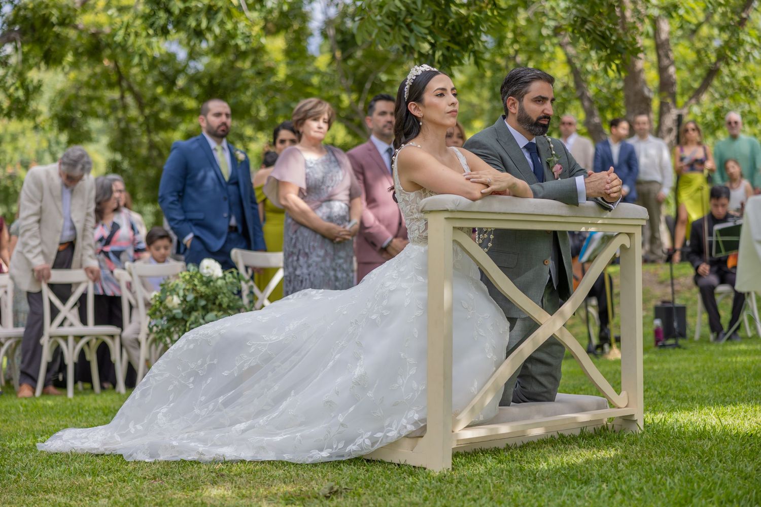 Wedding celebration outdoors with couple and guests seated at rustic wooden furniture. Boda en Parras Coahuila fotógrafo
