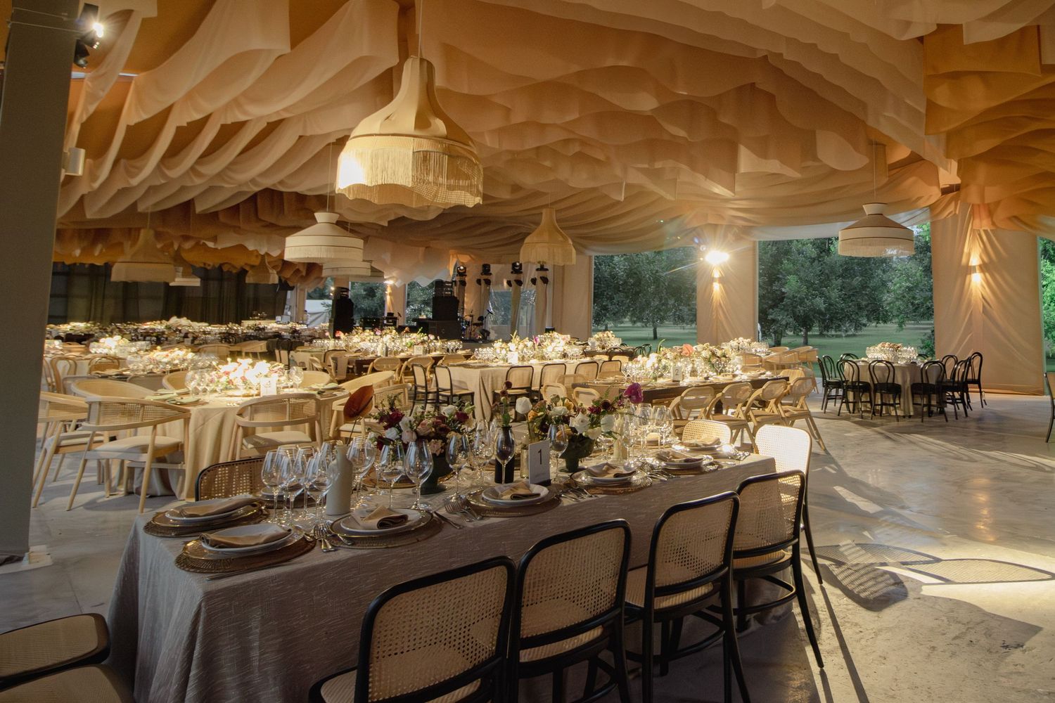 Panoramic view of an elegant wedding reception venue with white tablecloths and warm lighting creating a romantic atmosphere.