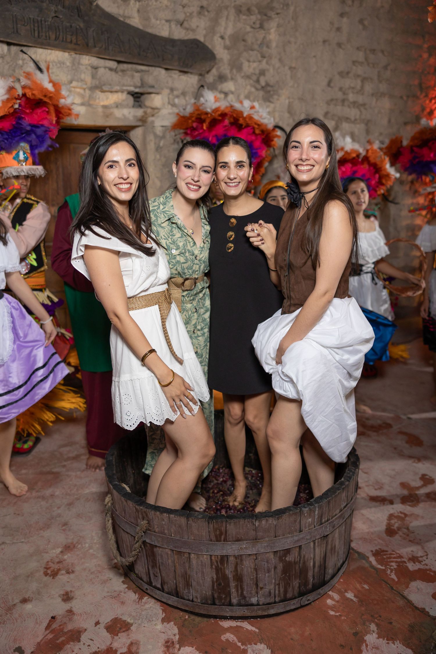 Four friends posing together inside a wooden wine barrel during a festive celebration. Boda en Parras Coahuila fotógrafo