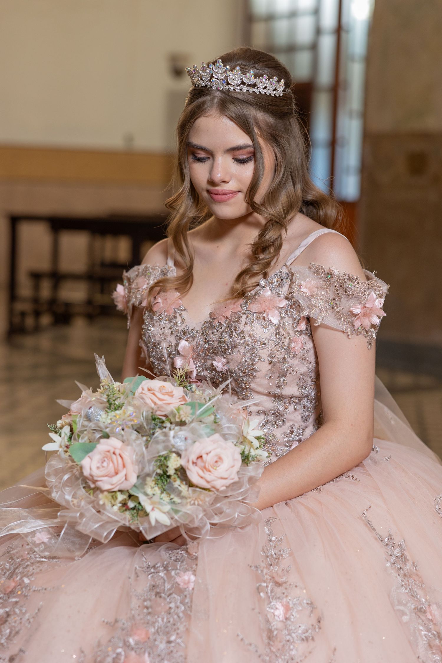 Close-up portrait of a celebrant wearing a blush pink beaded gown and crown holding a floral bouquet. Evento en Parras Coahuila , Fotógrafo