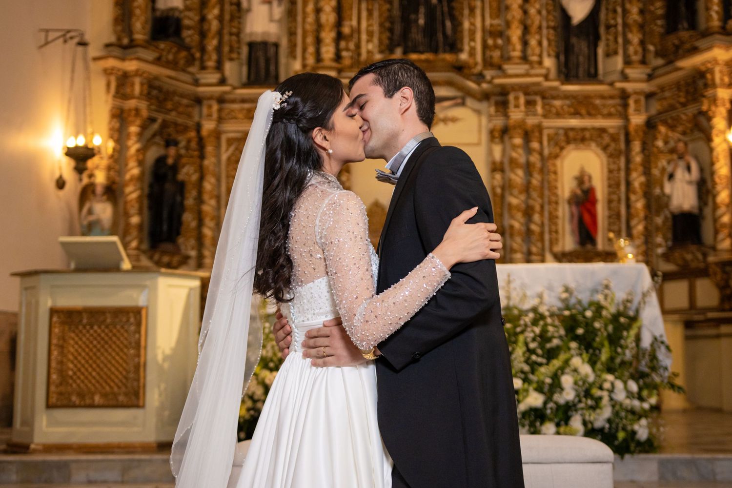 A romantic kiss between newlyweds in front of an ornate golden church altar. Boda en Parras Coahuila, Fotógrafo de bodas