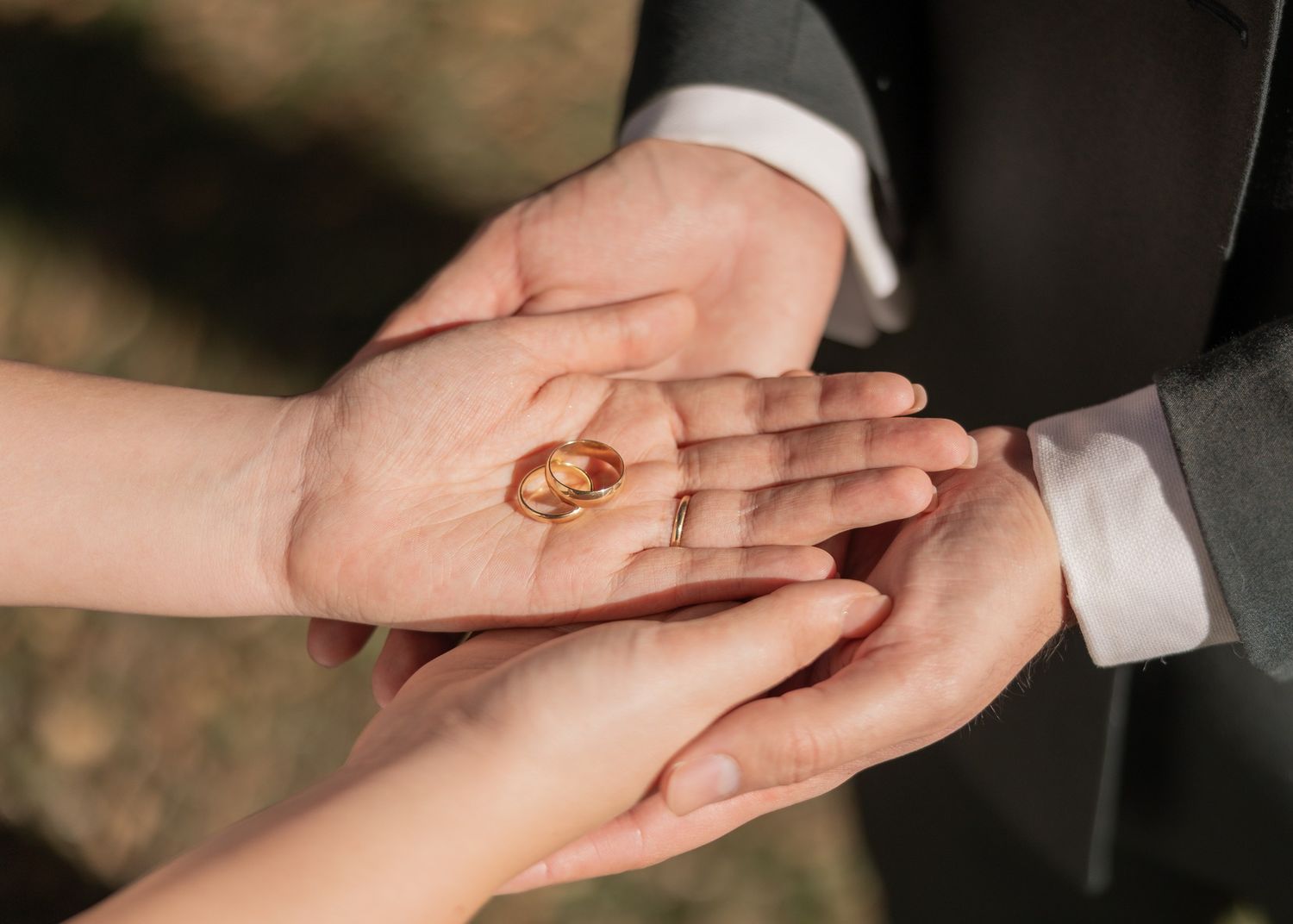 Close-up shots of hands with wedding rings being exchanged during a marriage ceremony.