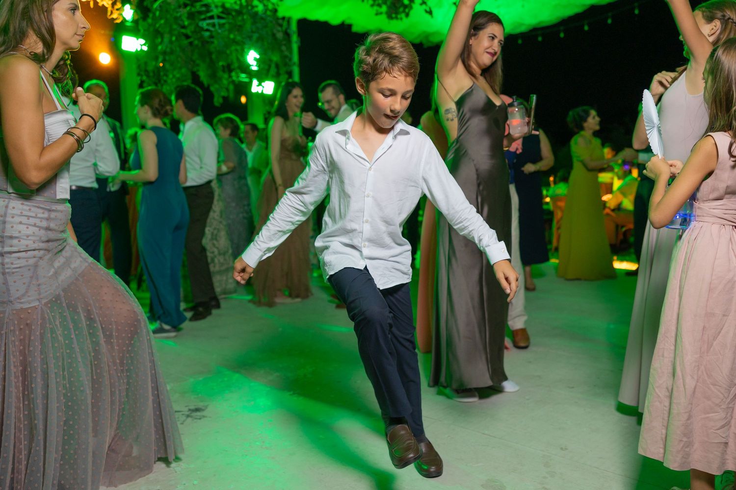 Young guest dancing at wedding reception under green party lights on dance floor. Boda en Parras Coahuila fotógrafo