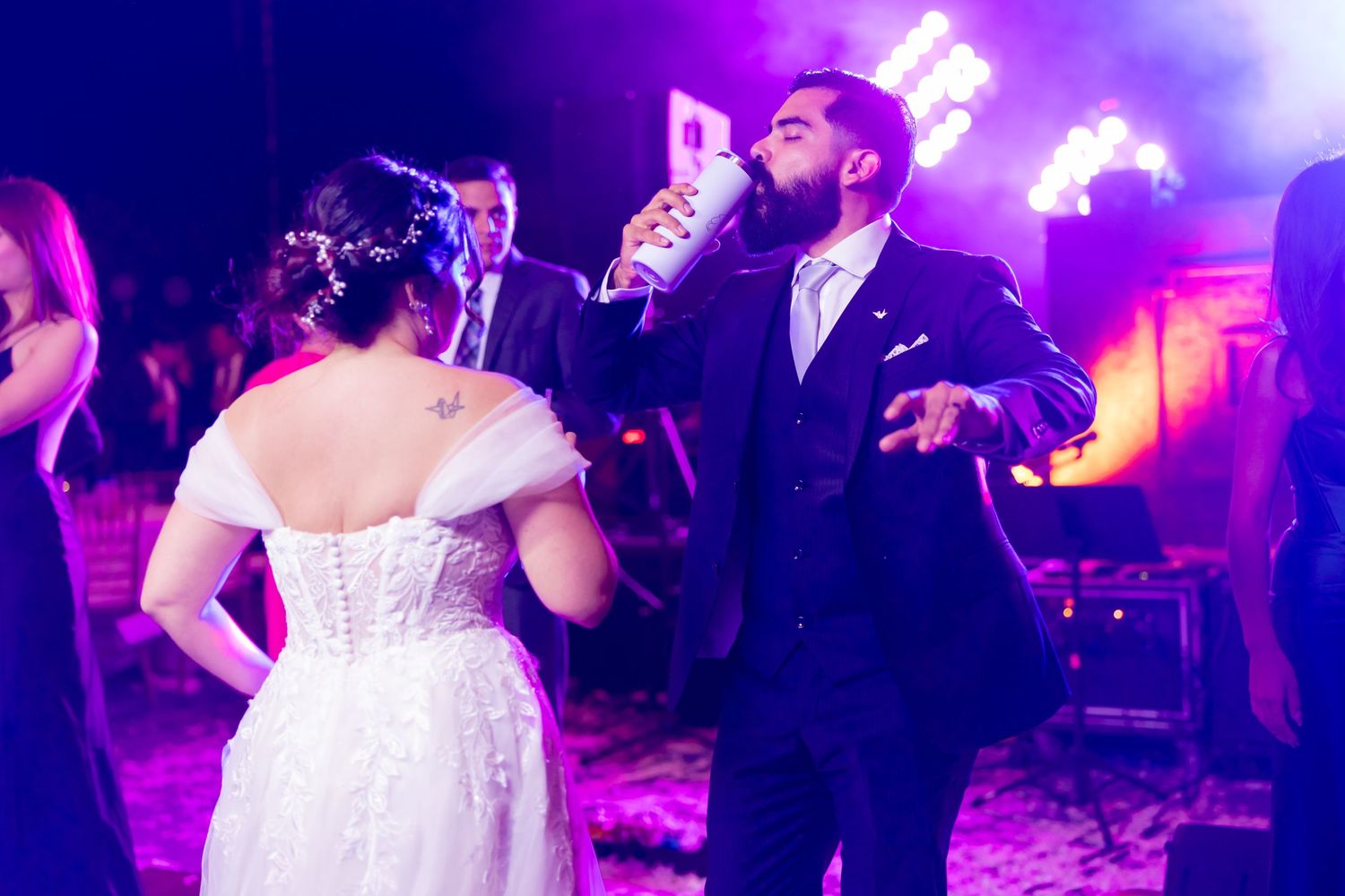 Couple dancing at their wedding reception illuminated by vibrant purple lighting. Boda en Parras Coahuila, Fotógrafo de bodas