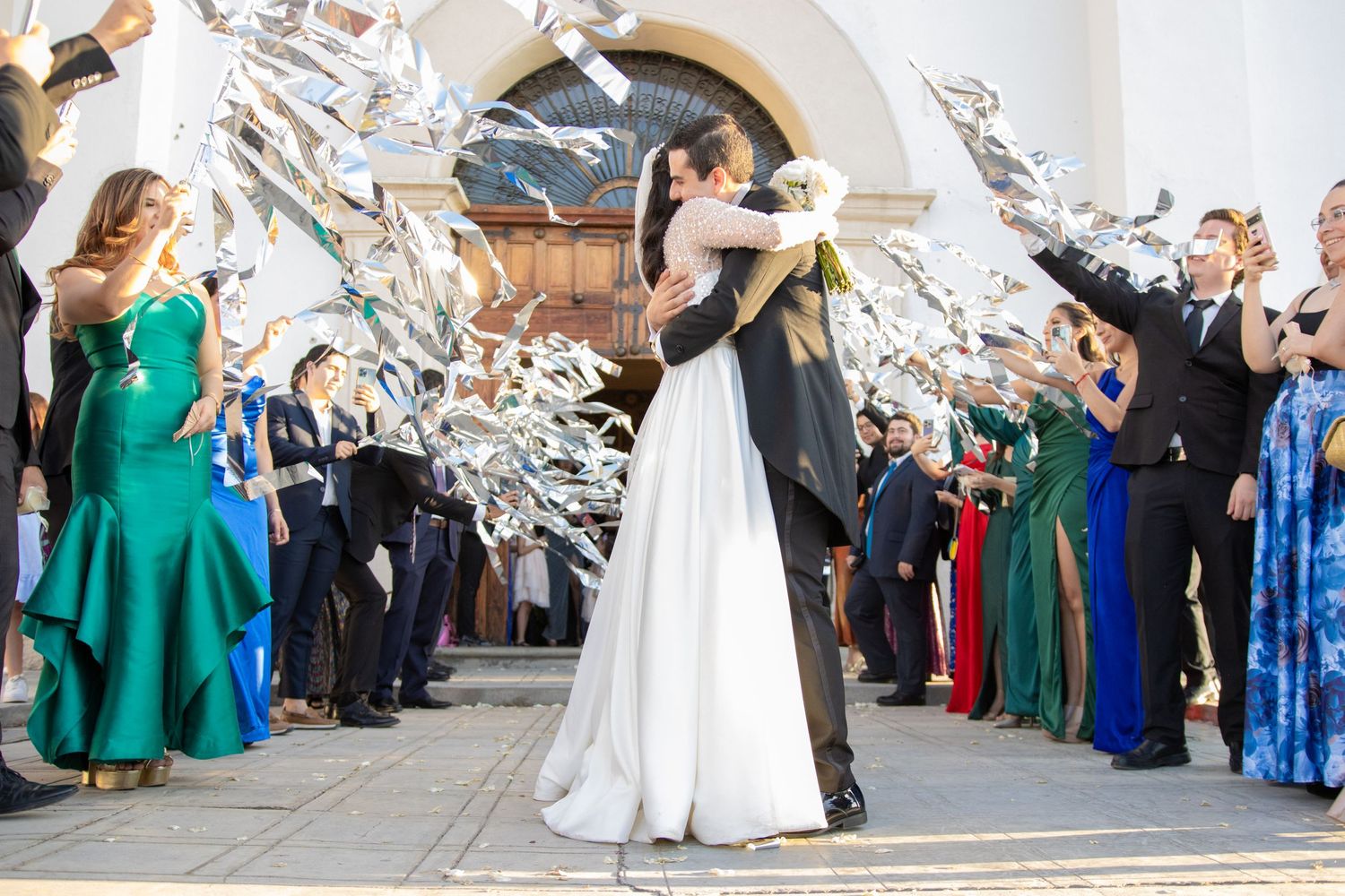 Wedding guests toss papers in celebration as newlyweds share their first kiss under an archway. Boda en Parras Coahuila, Fotógrafo de bodas