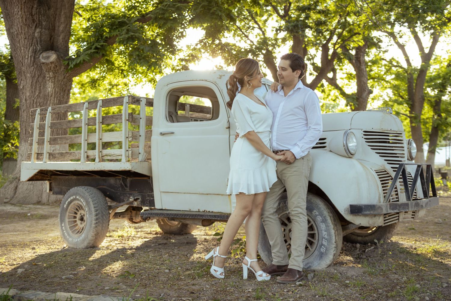 Couple poses together beside vintage pickup truck in dappled sunlight. boda en Parras Coahuila fotógrafo