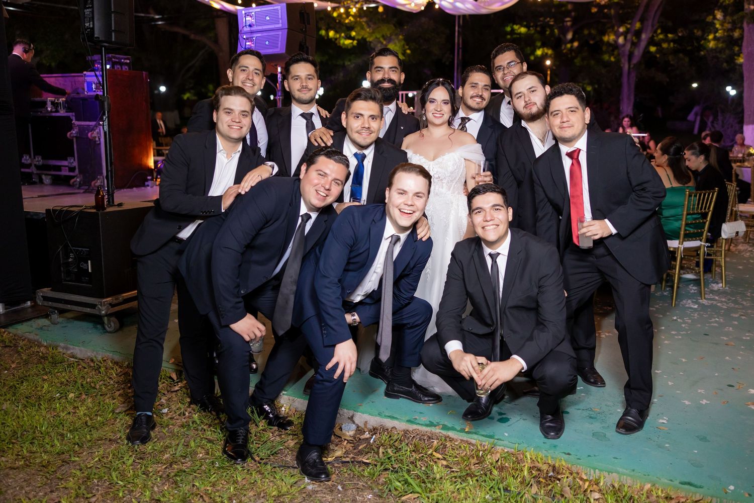 A group of formally dressed wedding guests pose together at an outdoor evening celebration. Boda en Parras Coahuila, Fotógrafo de bodas