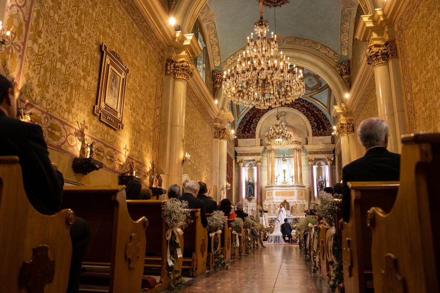 Ornate church interior with crystal chandelier and arched ceiling illuminated by warm lighting. Boda en Parras Coahuila fotógrafo