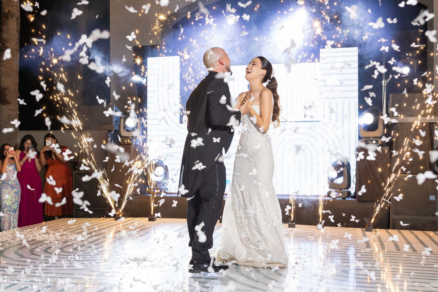 A wedding couple dances surrounded by sparklers and guests during their reception celebration.