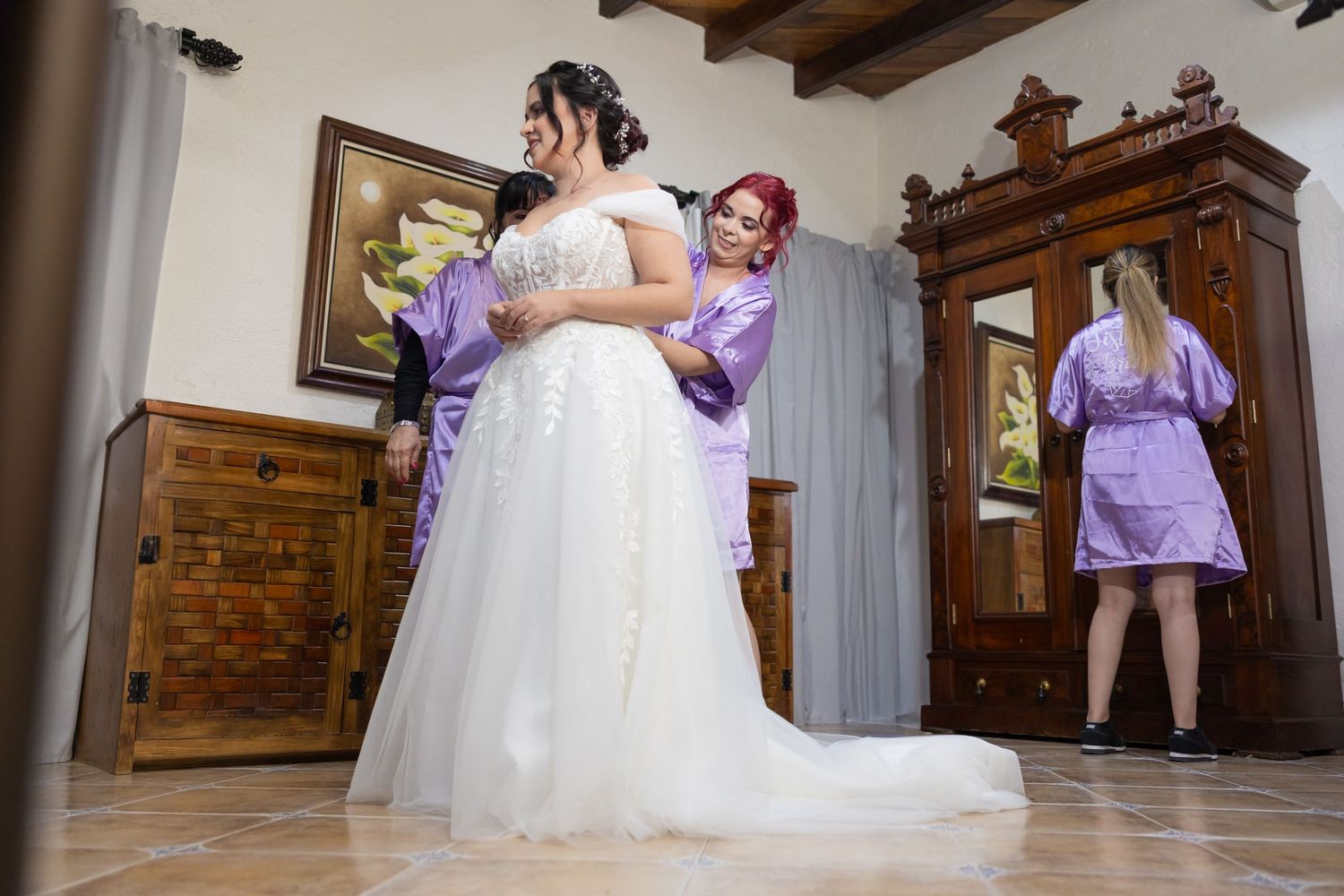 Wedding preparation scene with flowing white gown and attendants in purple robes. Boda en Parras Coahuila, Fotógrafo de bodas