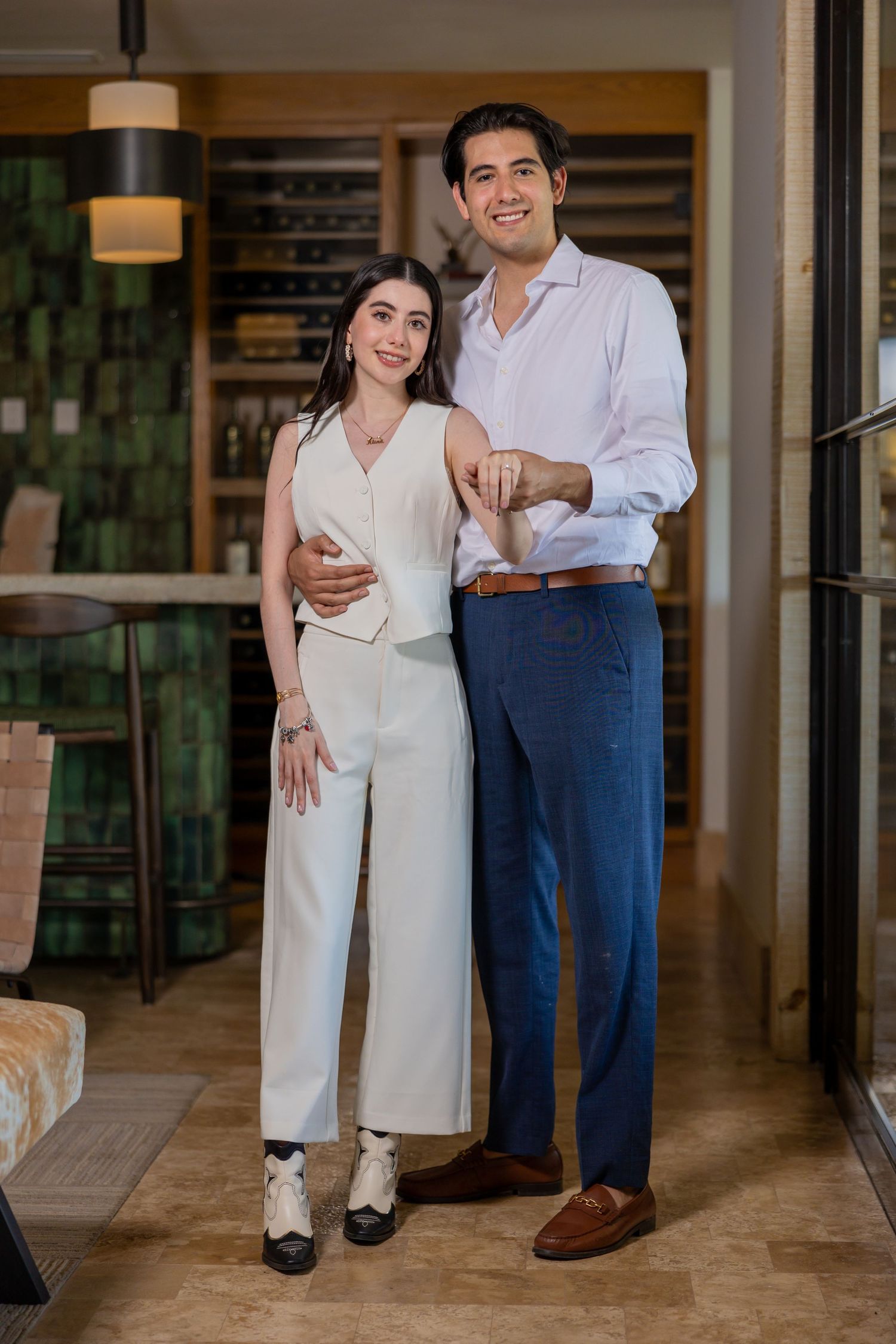 A couple in coordinated outfits poses standing together in an elegant indoor setting. Propuesta de matrimonio Parras, Fotografo