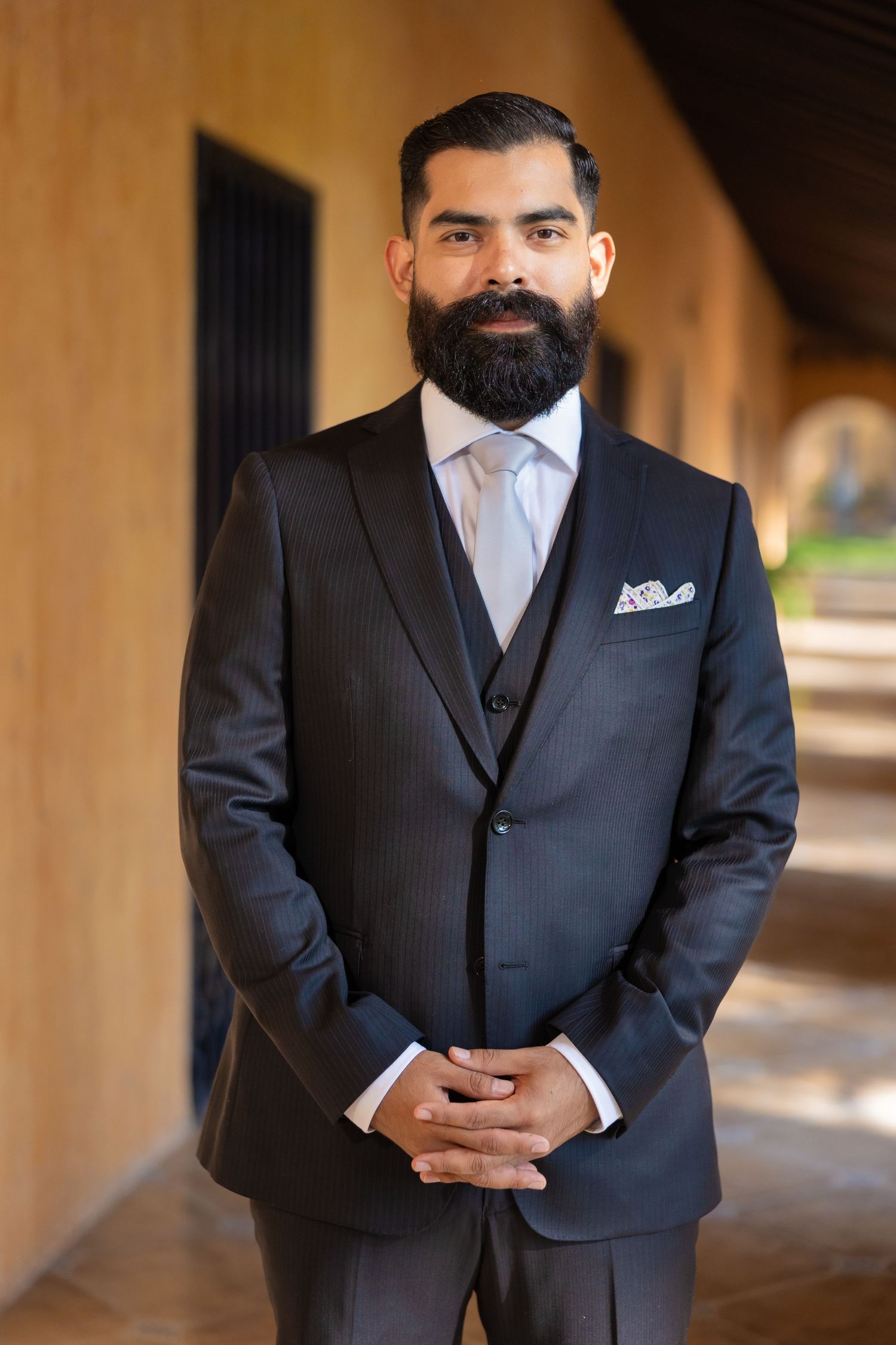 A formal portrait in a dark suit against warm terracotta architecture. Boda en Parras Coahuila, Fotógrafo de bodas