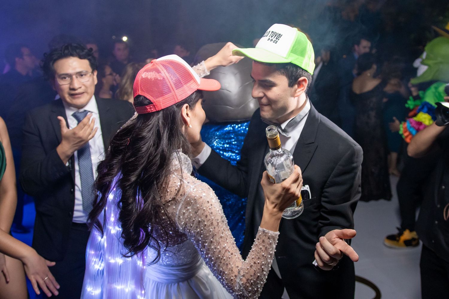 Guests wearing colorful baseball caps dance and celebrate at a formal party. Boda en Parras Coahuila, Fotógrafo de bodas