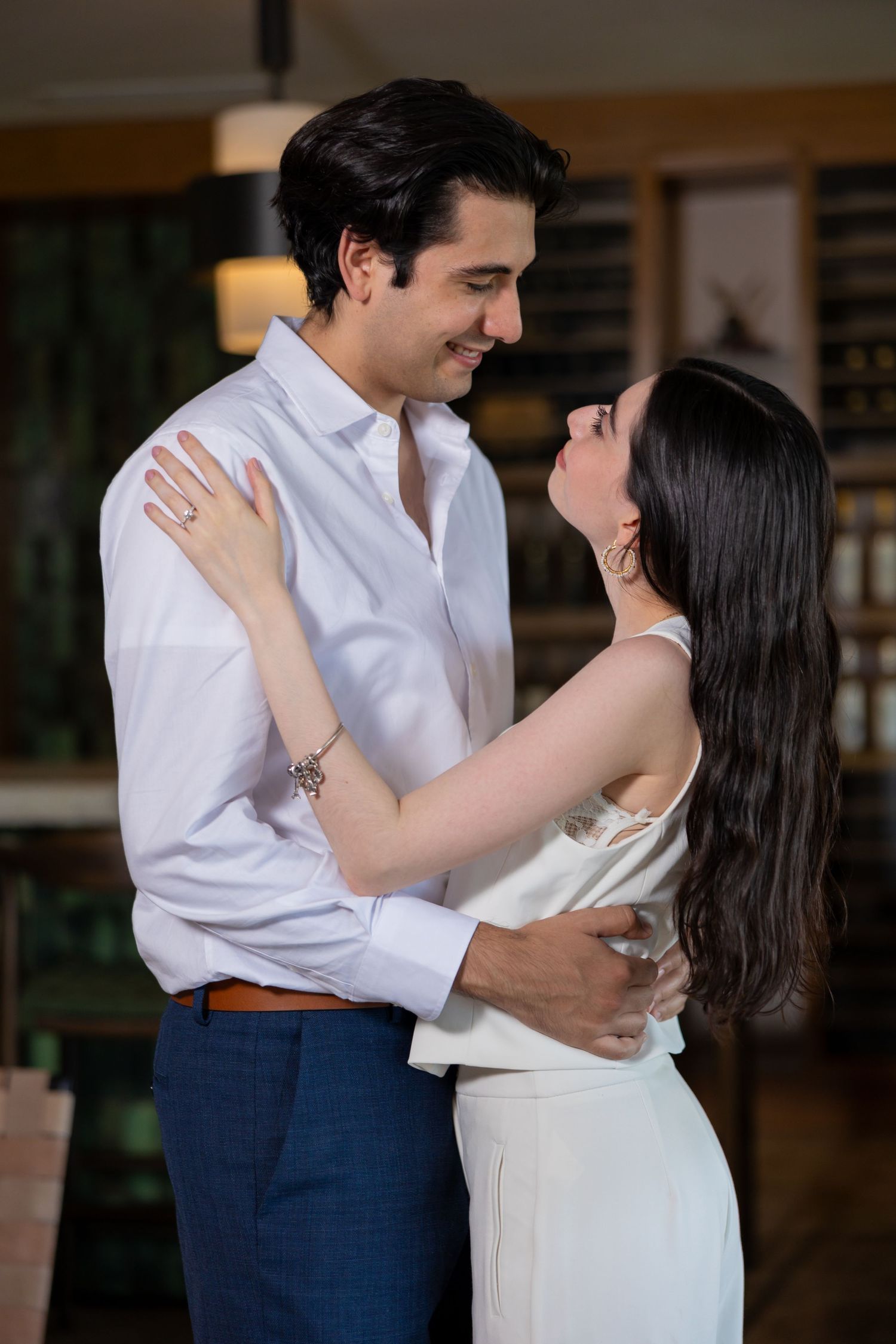 A tender moment shared between a couple in white and blue formal wear inside a warmly lit room. Propuesta de matrimonio Parras, Fotografo