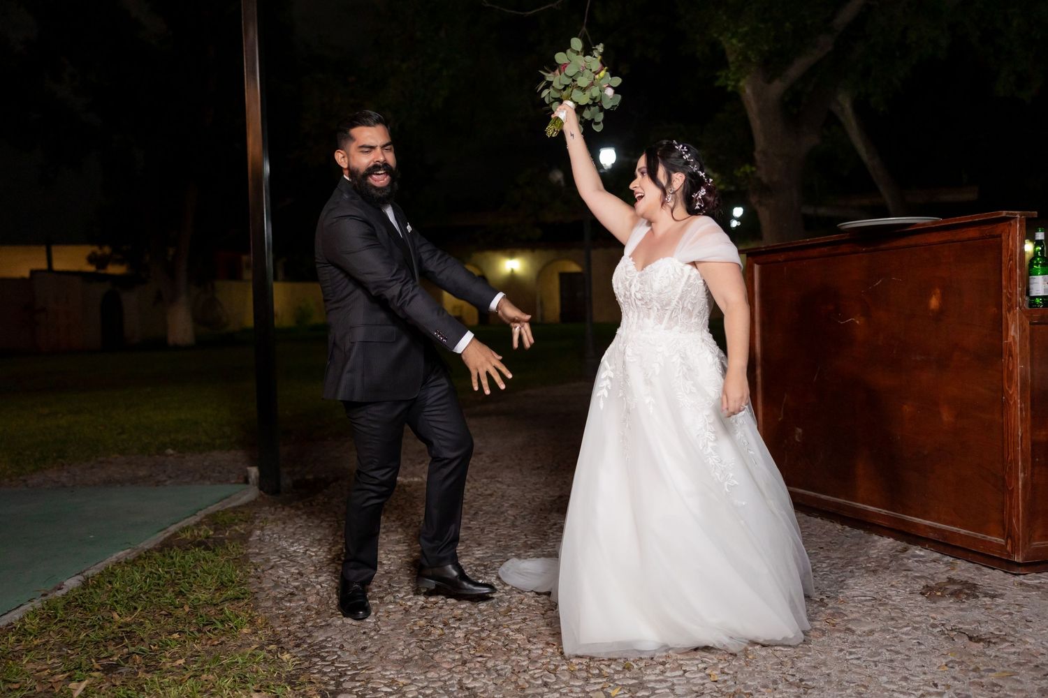 Newlyweds celebrate with playful pose during nighttime outdoor wedding reception. Boda en Parras Coahuila, Fotógrafo de bodas