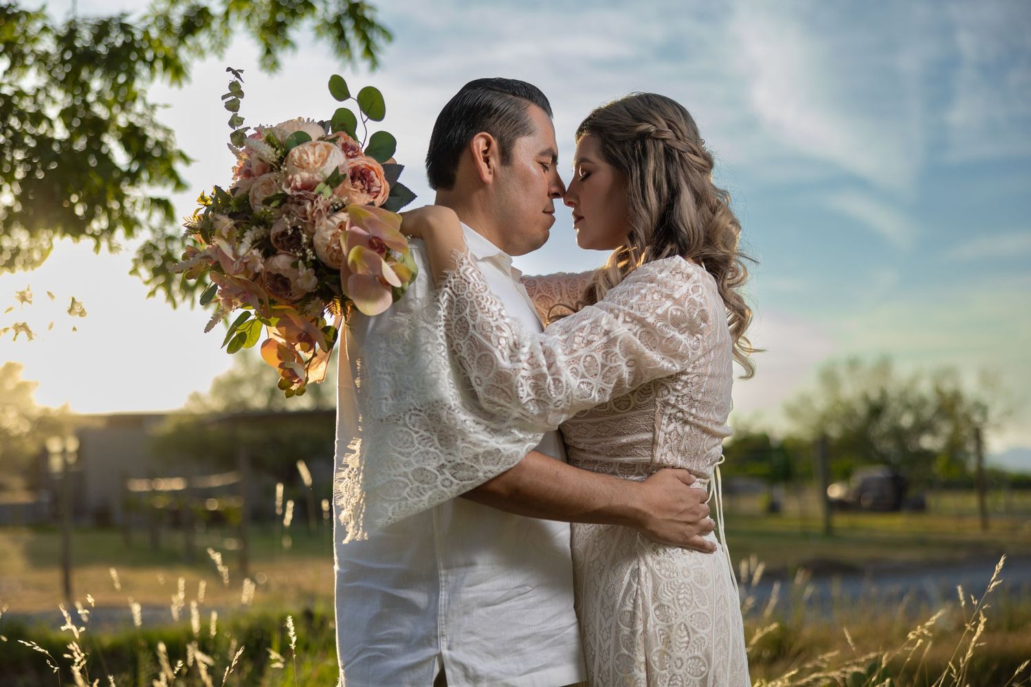 A romantic couple embracing in a field at sunset with a floral bouquet. Sesión en Parras Coahuila