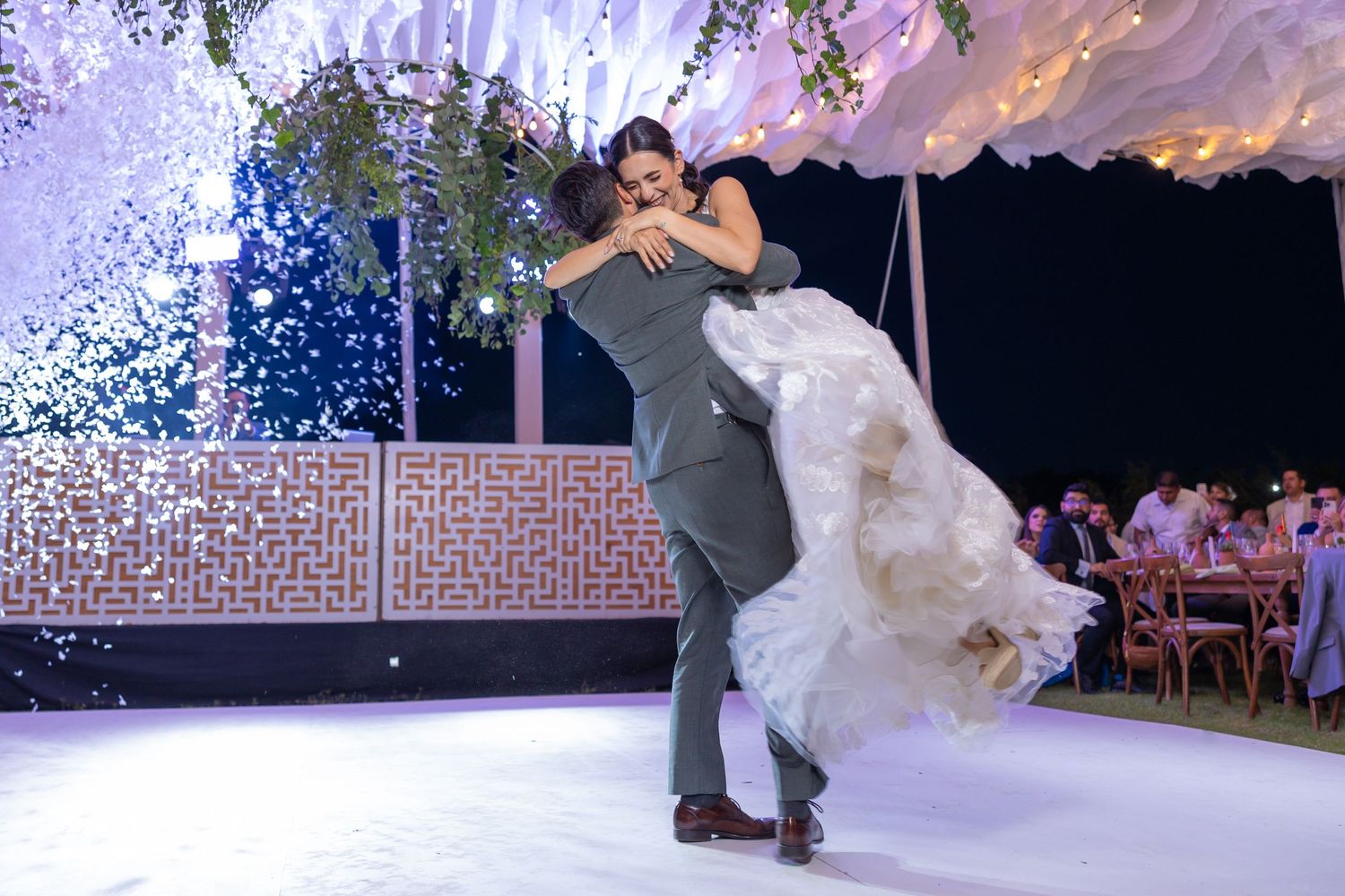 A couple performs a dramatic dance move on an illuminated dance floor under confetti. Boda en Parras Coahuila fotógrafo