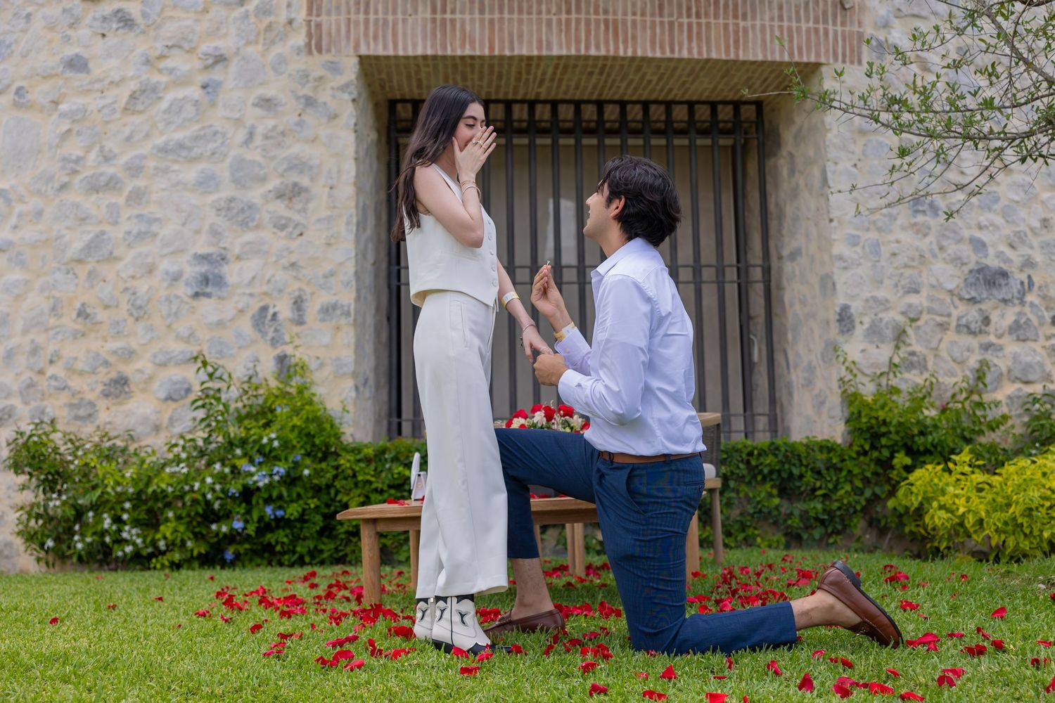 A heartfelt proposal moment captured in front of a stone wall with red rose petals. Propuesta de matrimonio Parras, Fotografo
