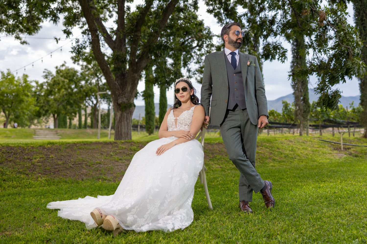 Wedding couple poses casually on grassy lawn with vineyard backdrop. Boda en Parras Coahuila fotógrafo