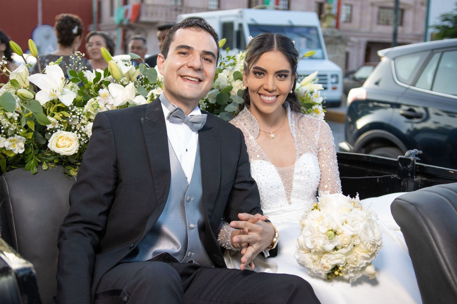 Newlyweds sit together in vintage car holding white floral bouquet at wedding celebration. Boda en Parras Coahuila, Fotógrafo de bodas