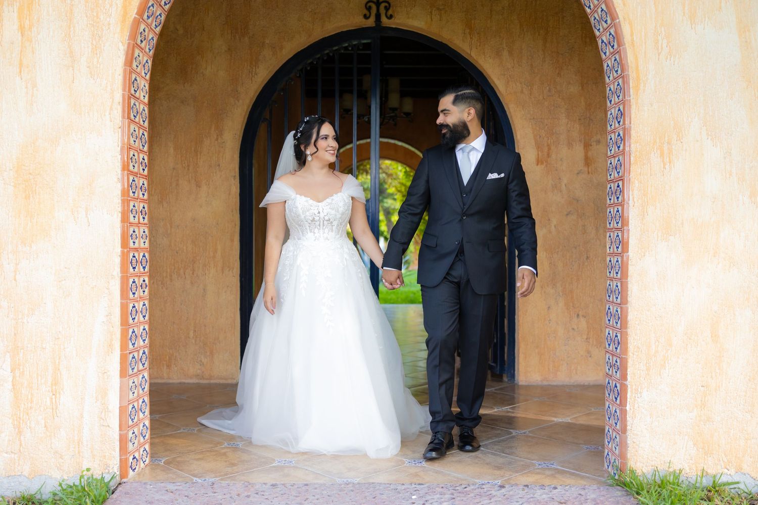 A newlywed couple stands in an elegant arched hallway with warm terracotta walls. Boda en Parras Coahuila, Fotógrafo de bodas
