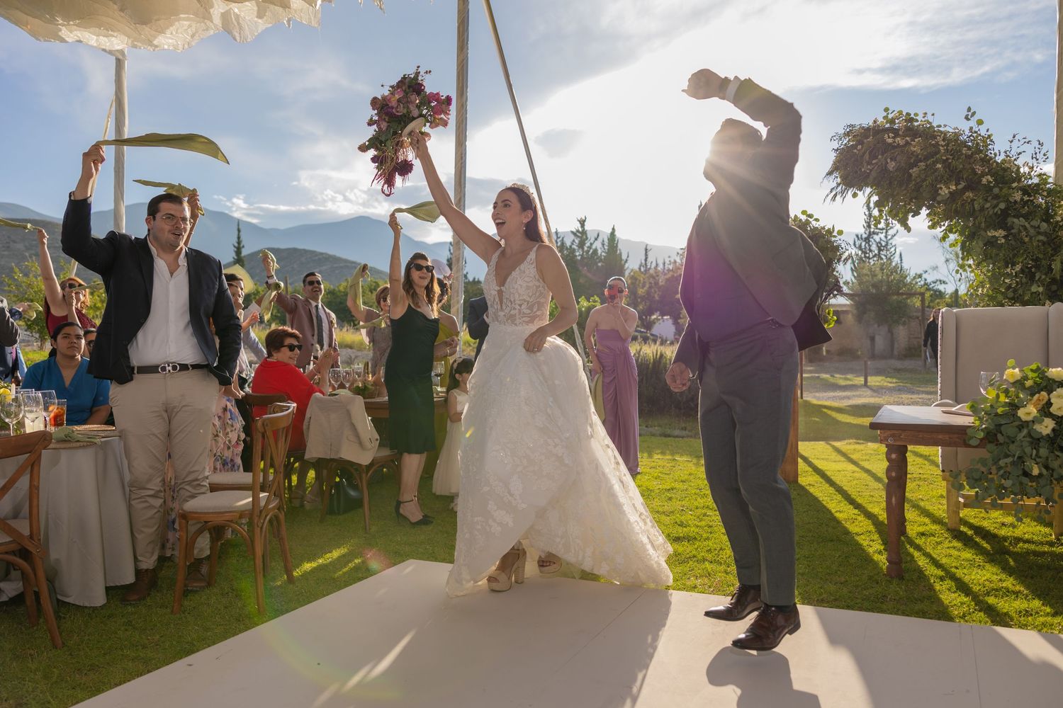 Wedding celebration outdoors with guests watching the couple dance on a white platform at sunset. Boda en Parras Coahuila fotógrafo